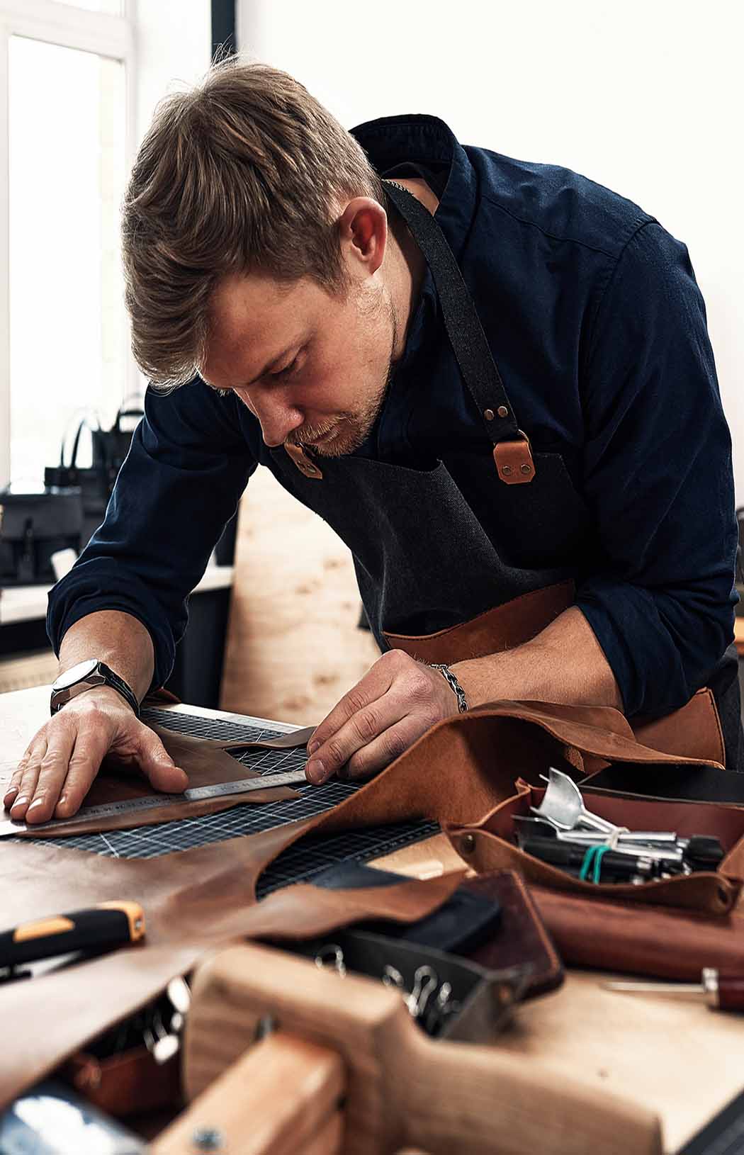 leather-craftsmen-working-making-measupenets-in-patterns-at-table-in-workshop-studio